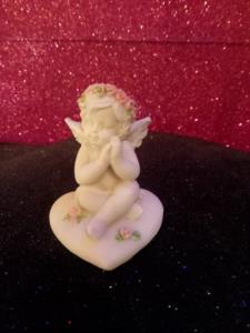 Cherubino seduto su cuore con rose