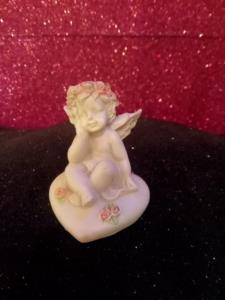 Cherubino seduto su cuore con rose